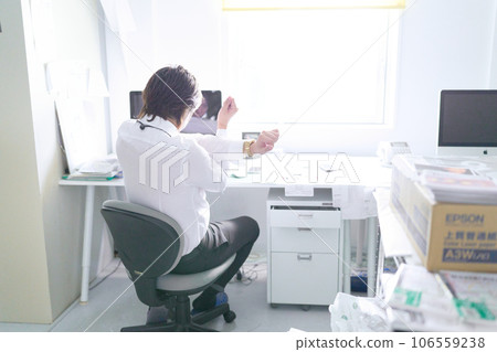 Rear view of a business person stretching at his desk 106559238