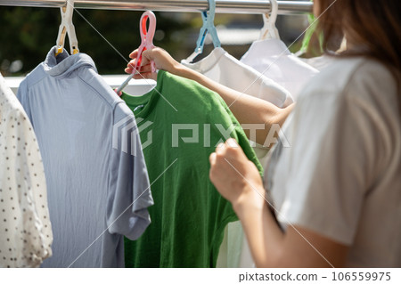 Young woman drying laundry on the veranda 106559975