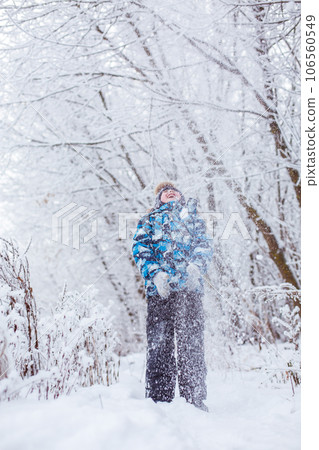 boy throwing snow in the air at sunny winter day, back view 106560549