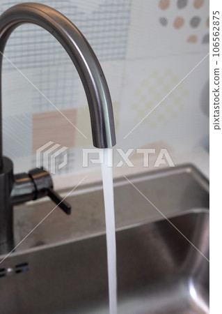 Water flowing out of a stainless steel tap. Kitchen room 106562875