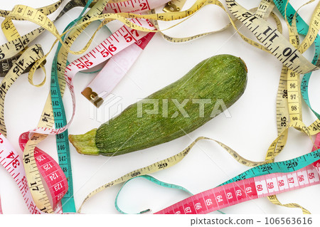 Zucchini with measuring tape on white background Zucchini with measuring tape on white background 106563616