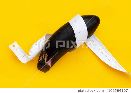 Eggplant with measuring tape on yellow background. Eggplant with measuring tape on yellow background. 106564107