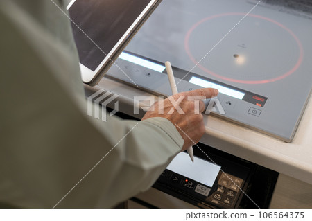 A male contractor inspecting the area around an IH stove during a regular inspection of a newly built detached house. A male contractor inspecting the area around an IH stove during a regular inspection of a newly built detached house. 106564375