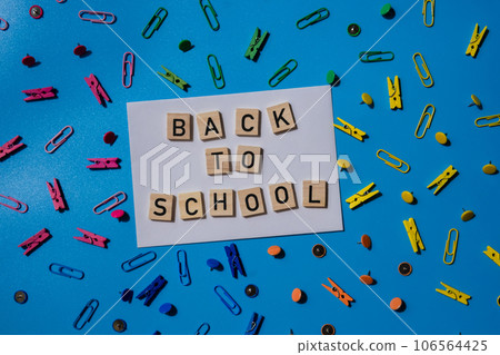 Educational greeting announcement for students and teacher. Saying BACK TO SCHOOL text on wooden blocks on creative vivid background with stationery supplies around. Concept of new school year Educational greeting announcement for students and teacher. Saying BACK TO SCHOOL text on wooden blocks on creative vivid background with stationery supplies around. Concept of new school year 106564425