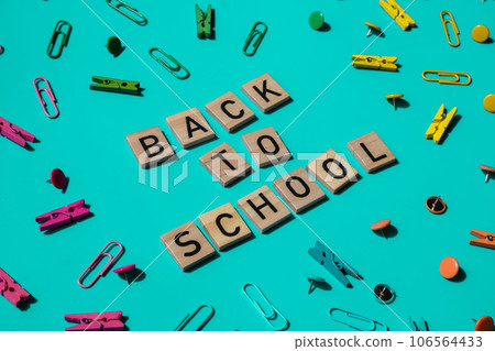 Educational greeting announcement for students and teacher. Saying BACK TO SCHOOL text on wooden blocks on creative vivid background with stationery supplies around. Concept of new school year 106564433