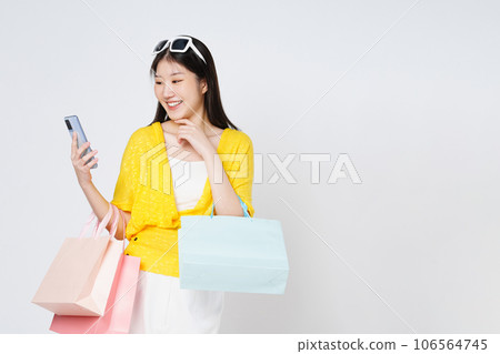 Young woman holding shopping bags while using mobile phone isolated over white background. 106564745