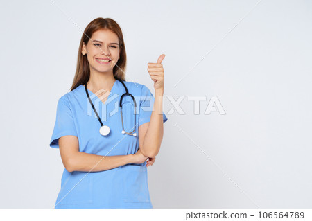 Portrait of smiling young woman doctor with stethoscope showing thumbs up isolate on white background. 106564789