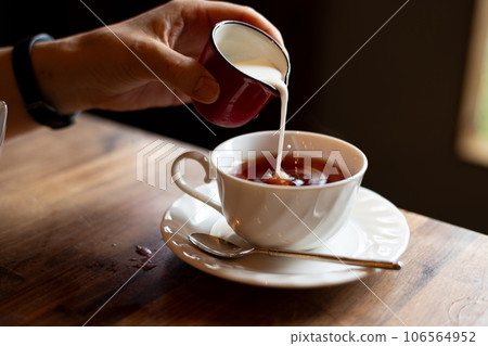 Pouring milk into tea 106564952