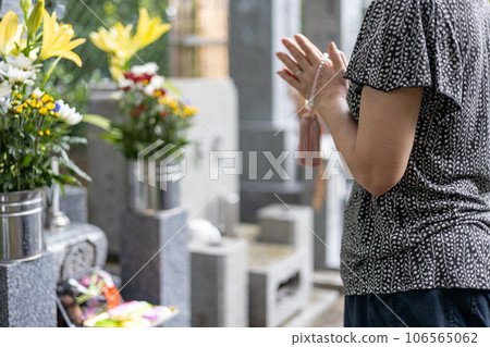 A senior woman who came to visit a grave and put her hands together with a rosary 106565062