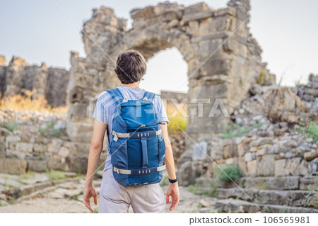 Man tourist explores Aspendos Ancient City. Aspendos acropolis city ruins, cisterns, aqueducts and old temple. Aspendos Antalya Turkey. turkiye 106565981