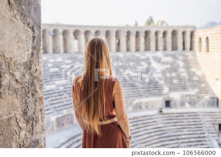 Woman tourist explores Aspendos Ancient City. Aspendos acropolis city ruins, cisterns, aqueducts and old temple. Aspendos Antalya Turkey. turkiye 106566000