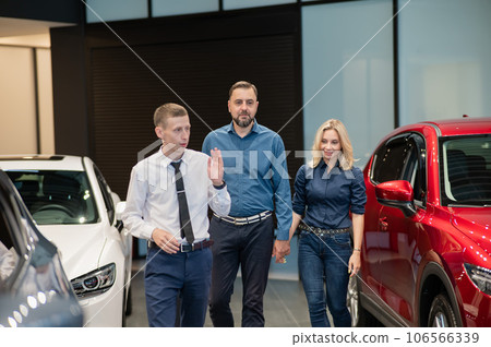 The seller helps a caucasian couple to choose a car.  106566339