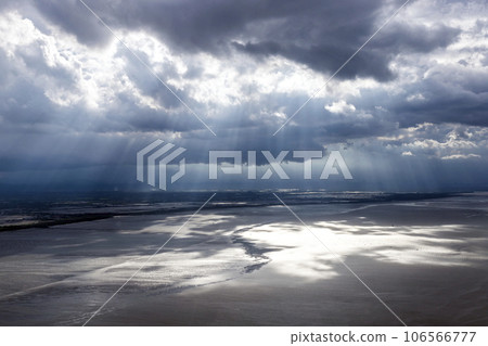 A wide-angle shot of the sun shining through clouds onto the land and sea beach. represents the power of nature. The sun is the power of life. The light from the sun nourishes all living things. A wide-angle shot of the sun shining through clouds onto the land and sea beach. represents the power of nature. The sun is the power of life. The light from the sun nourishes all living things. 106566777