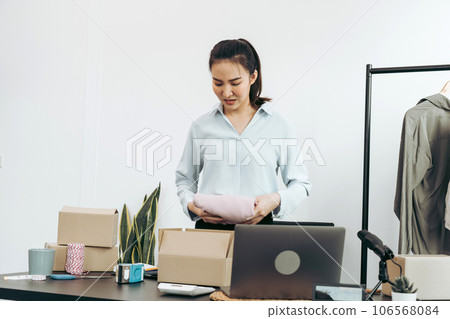 Asian entrepreneur is preparing her clothes that can be sold in paper boxes for delivery to customers. 106568084