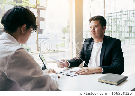 Male manager is talking or explaining about having to dismiss the employee while being handed out a resignation envelope to the employee. 106568129