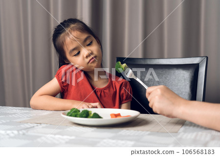 Little cute kid girl refusing to eat healthy vegetables. Children do not like to eat vegetables. Little cute kid girl refusing to eat healthy vegetables. Children do not like to eat vegetables. 106568183