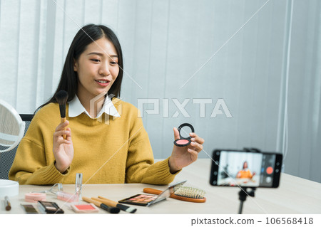 Asian teenage girls doing makeup vlogs and using a video mobile camera to record vlogs and publish them online at home. Asian teenage girls doing makeup vlogs and using a video mobile camera to record vlogs and publish them online at home. 106568418