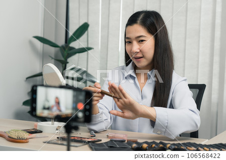 Young asian woman vlogging herself about beauty products with making a video for her blog on cosmetics using phone camera at home. Young asian woman vlogging herself about beauty products with making a video for her blog on cosmetics using phone camera at home. 106568422