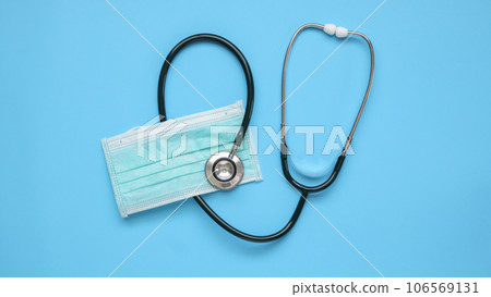 Stethoscope medical equipment with surgical face mask on blue background covid-19 Coronavirus prevention healthcare concept 106569131