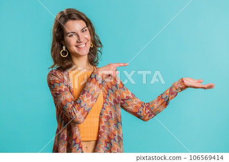 Young woman showing thumbs up and pointing at left on blank space, place for your advertisement logo 106569414