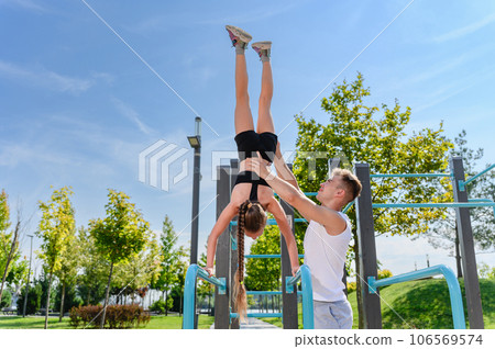 Girl doing hand stand push ups exercise in parallel bars 106569574