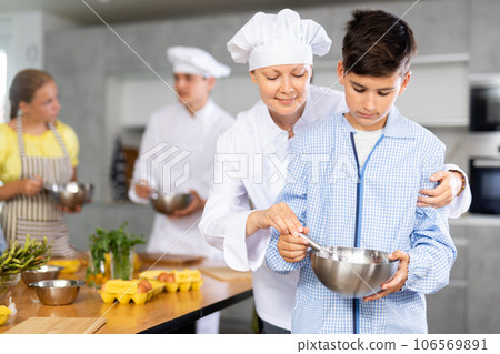 Adult woman cook helps boy cook Adult woman cook helps boy cook 106569891