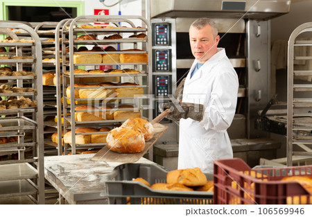 Baker takes out hot bread from the oven Baker takes out hot bread from the oven 106569946
