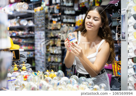 Female buyer holds in hands tests ceramic figurine in memorable gifts shop Female buyer holds in hands tests ceramic figurine in memorable gifts shop 106569994