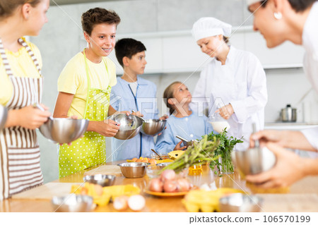 Young guy and adult woman cook teaches group of children to cook 106570199