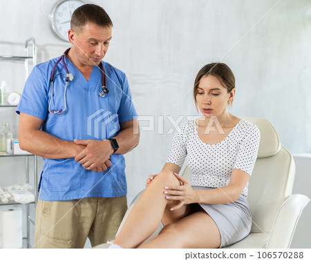 Young woman patient having her knee examined by doctor 106570288