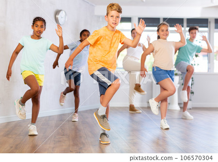 Boy dances vogue in choreographic school, friends and teacher dance in gym blurry background 106570304