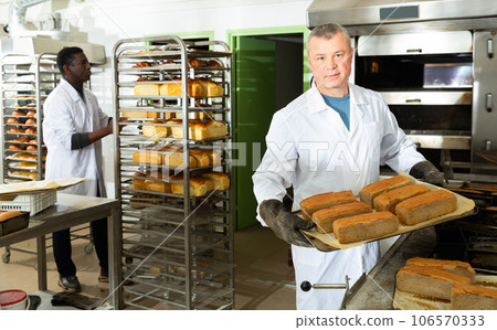 Successful baker spreads freshly baked bread on a pallet Successful baker spreads freshly baked bread on a pallet 106570333