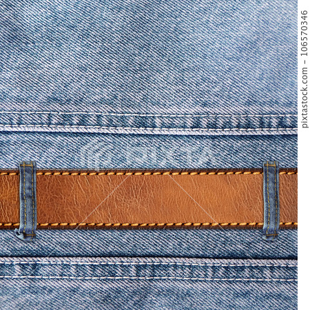Blue denim background with leather belt. Horizontal or vertical backdrop with light blue color denim jeans fabric texture and brown leather strap. Copy space for text 106570346