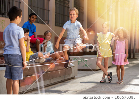 Little boy jumping on rubber band with friends in historical center 106570393