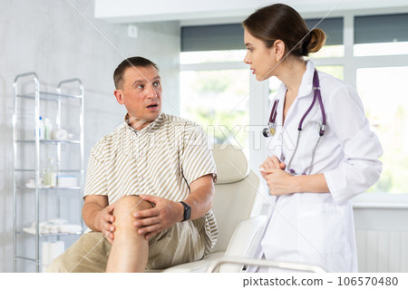 Middle-aged man patient having his knee examined by doctor 106570480