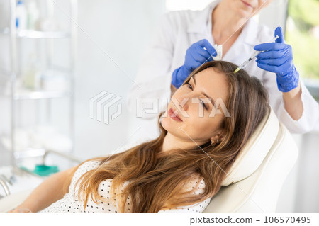 Relaxed young woman undergoing hair mesotherapy procedure 106570495