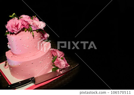 Cutting a delicious pink wedding birthday cake on a serving table Cutting a delicious pink wedding birthday cake on a serving table 106570511