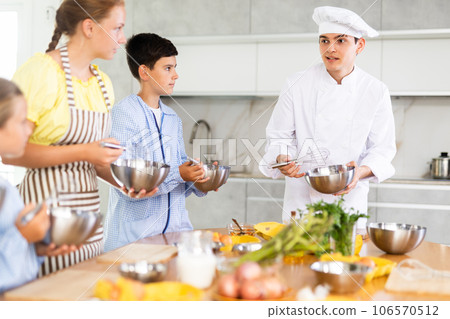 Friendly young chef running culinary courses for group of children 106570512