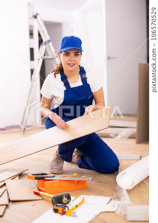 Woman builder puts laminate on the floor in room Woman builder puts laminate on the floor in room 106570529