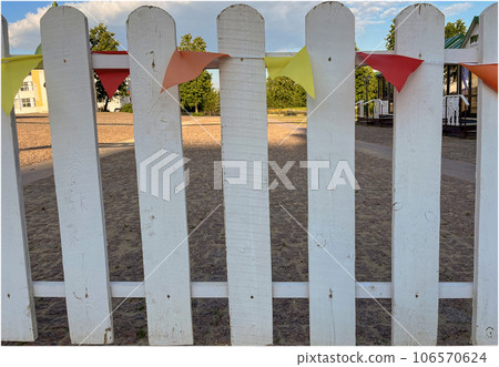 multicolored flags hang on a wooden fence 106570624