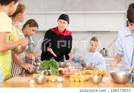 At cooking course, woman cook in black suit tells children about rules of cooking fluffy pancakes. 106570653