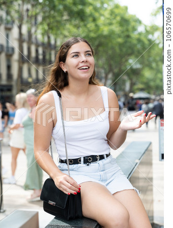 Cheerful girl sitting on La Rambla street during walk through summer Barcelona 106570699