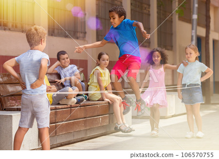 Mexican boy playing rubber band jumping game with friends 106570755