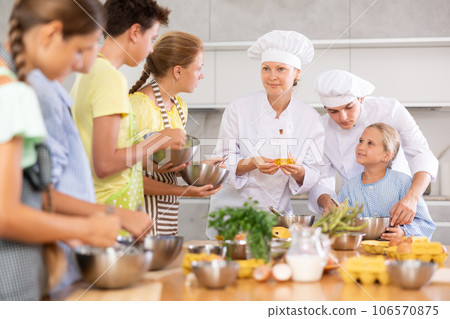 Two friendly chefs giving culinary lesson to group of tweens 106570875