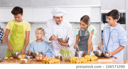 In cooking class, guy cook with bowl in hands tells children participants culinary ticks and tricks 106571090