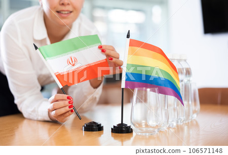 Woman placing flag of Iran and rainbow flag on negotiating table Woman placing flag of Iran and rainbow flag on negotiating table 106571148