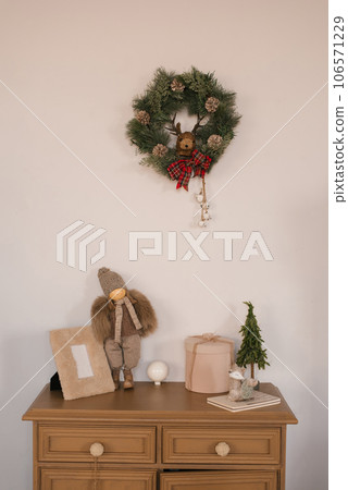 Wooden chest of drawers with Christmas decor, toy, photo frame, wreath in the children's room Wooden chest of drawers with Christmas decor, toy, photo frame, wreath in the children's room 106571229