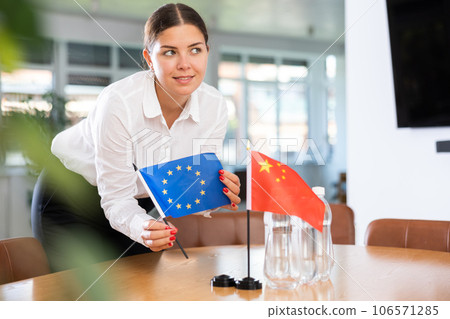 Young lady sets miniatures flags of China and European Union before international negotiations 106571285