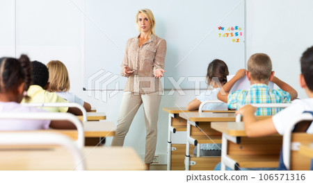 Female teacher conducting lesson with preteen pupils at whiteboard 106571316