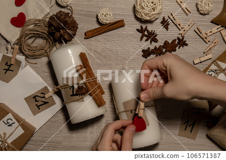 Unrecognizable young woman paint numbers on candles. Female making homemade advent calendar Made with your own hands step by step DIY crafts do it yourself. Preparation to christmas concept. Seasonal 106571387